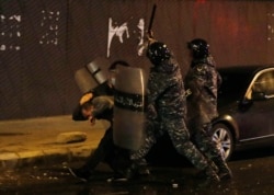 Riot police officers beat an anti-government protester during a protest near the parliament square in downtown Beirut, Lebanon, Dec. 14, 2019.