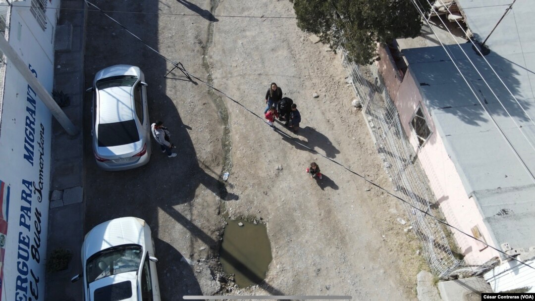 A las afueras del albergue El Buen Samaritano de Ciudad Juárez, México, niños migrantes miran hacia un dron que vuela sobre el edificio durante una visita de periodistas al área el 24 de enero 2024.