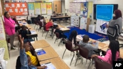 Students answer questions as they read a book with third-grade teacher La'Neeka Gilbert-Jackson, right, at Boyd Elementary School in Atlanta, Dec. 15, 2022.