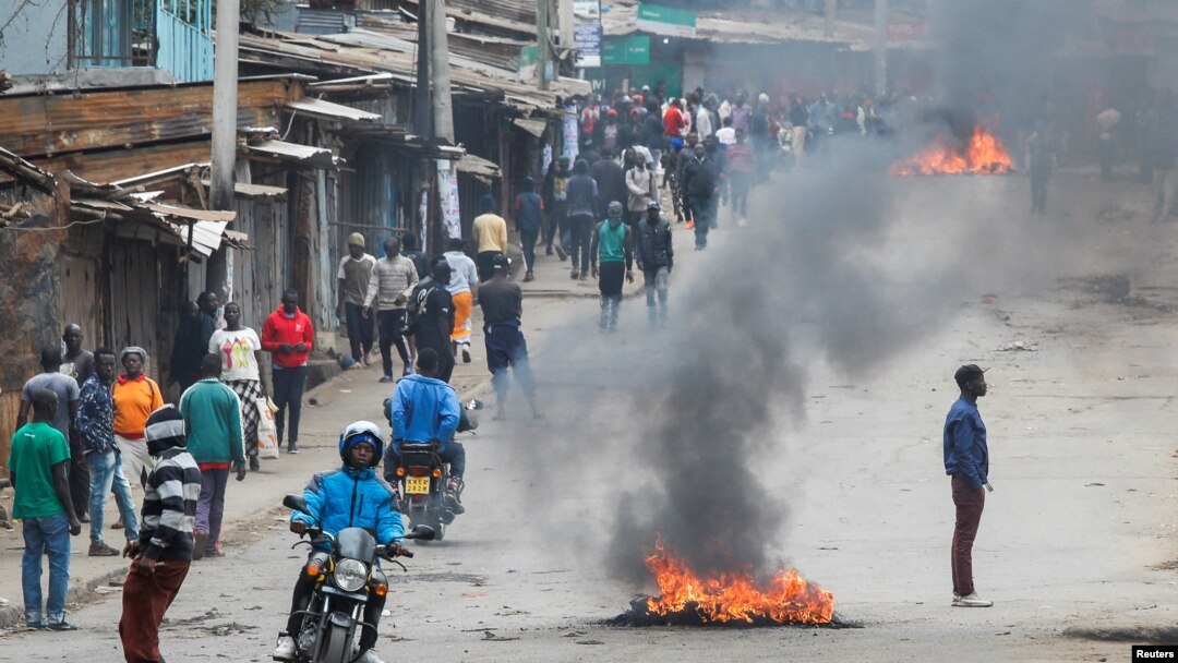 A person rides a bike past tires set on fire by protestors in Kibera slum during an anti-government protest against the imposition of tax hikes by the government in Nairobi, Kenya July 19, 2023.