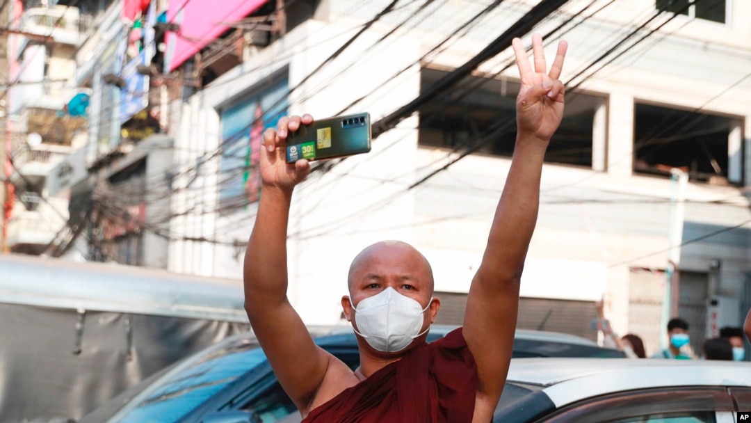 FILE - A Buddhist monk flashes a three-fingered salute and holds a smart phone during a protest in Yangon, Myanmar, Feb. 7, 2021. Myanmar’s military government is now blocking VPNs, which help internet users bypass restrictions to access websites and social media. 
