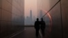 A man stands in the Empty Sky 911 Memorial in Jersey City, N.J., looking toward the One World Trade Center tower in New York City shortly after sunrise as haze and smoke caused by wildfires in Canada hangs over the Manhattan skyline, June 8, 2023. 