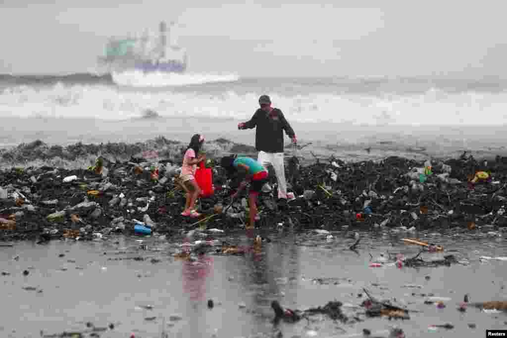 People collect recyclable materials after heavy storms washed large amounts of garbage onto a beach in Acajutla, El Salvador, June 19, 2024.