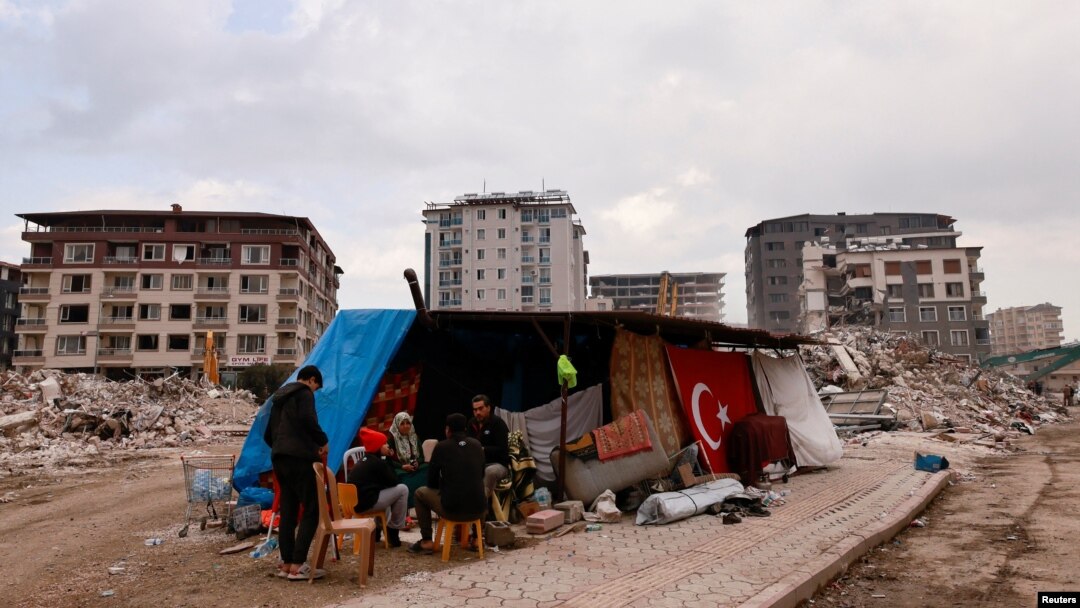 A family sits in an improvised shelter after their apartment building collapsed in an earthquake, in Antakya, southeastern Turkey, Feb. 21, 2023.