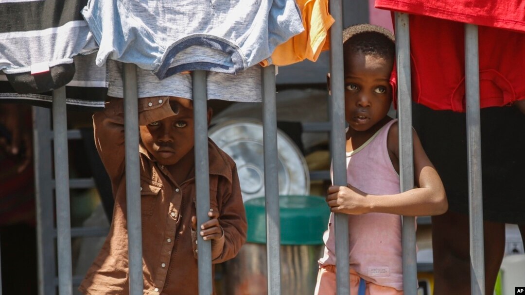 Children look through a fence at a shelter for families displaced by gang violence, in Port-au-Prince, Haiti, March 13, 2024. 