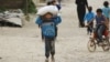 FILE - A boy carries food aid given by UN's World Food Program in Raqqa, Syria, April 26, 2018.