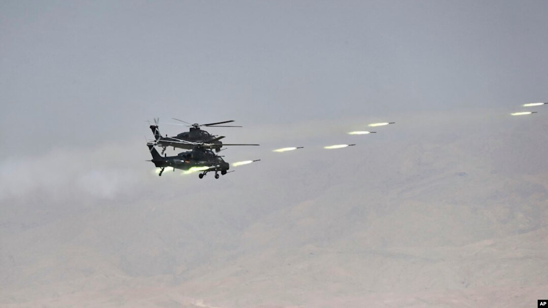 FILE - In this handout photo released by Russian Defense Ministry Press Service, Chinese military helicopter gunships fire rockets during joint war games held by Russia and China in northwestern China, Aug. 13, 2021. 