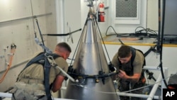 Senior Airman Jacob Deas, 23, left, and Airman 1st Class Jonathan Marrs, 21, right, secure the titanium shroud at the top of a Minuteman III intercontinental ballistic missile on Aug. 24, 2023, at the Bravo 9 silo at Malmstrom Air Force Base in Montana. (U.S. Air Force)