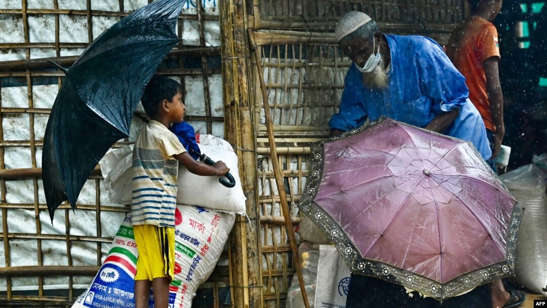 FILE - Rohingya refugees wait at a food distribution place during monsoon rainfall in Kutupalong refugee camp in Ukhia, Bangladesh, August 10, 2022.