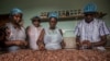 FILE - Workers at Moments Chocolate workplace remove husks from cocoa beans on June 18, 2019 in Accra. 