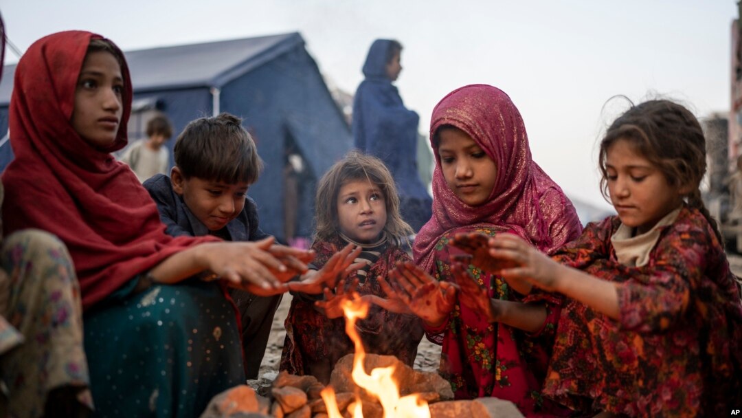 FILE - Afghan refugee children warm themselves near the Torkham Pakistan-Afghanistan border crossing in Torkham, Afghanistan, Nov. 4, 2023, after their repatriation from Pakistan. More than 800,000 Afghans are expected to return to Afghanistan this year; about half are children.
