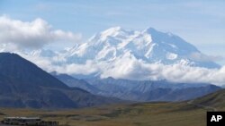 FILE - Sightseeing buses and tourists are seen at a pullout popular for taking in views of North America's tallest peak, Denali, in Denali National Park and Preserve, Alaska, Aug. 26, 2016.