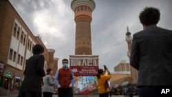 Watalii wakipiga picha karibu na mnara kwenye eneo la International Grand Bazaar katika mkoa wa magharibi mwa China wa Xinjiang, Aprili 21, 2021.