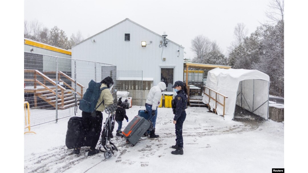 FILE - A family crosses into Canada at Roxham Road, an unofficial crossing point from New York State to Quebec for asylum-seekers, in Champlain, N.Y., March 25, 2023. (REUTERS/Carlos Osorio)