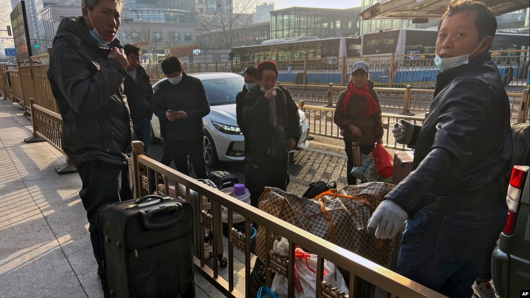 2023年1月6日北京: 帶著行李的移工搭火車前在西站外休息。