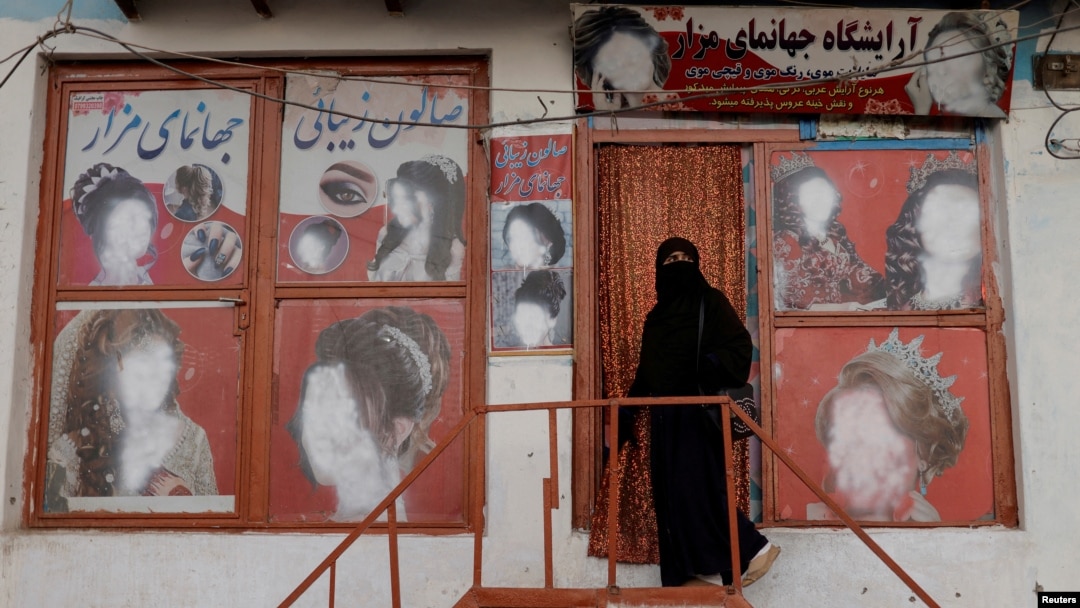 FILE - A woman wearing a niqab enters a beauty salon where the ads of women have been defaced by a shopkeeper in Kabul, Oct. 6, 2021. 