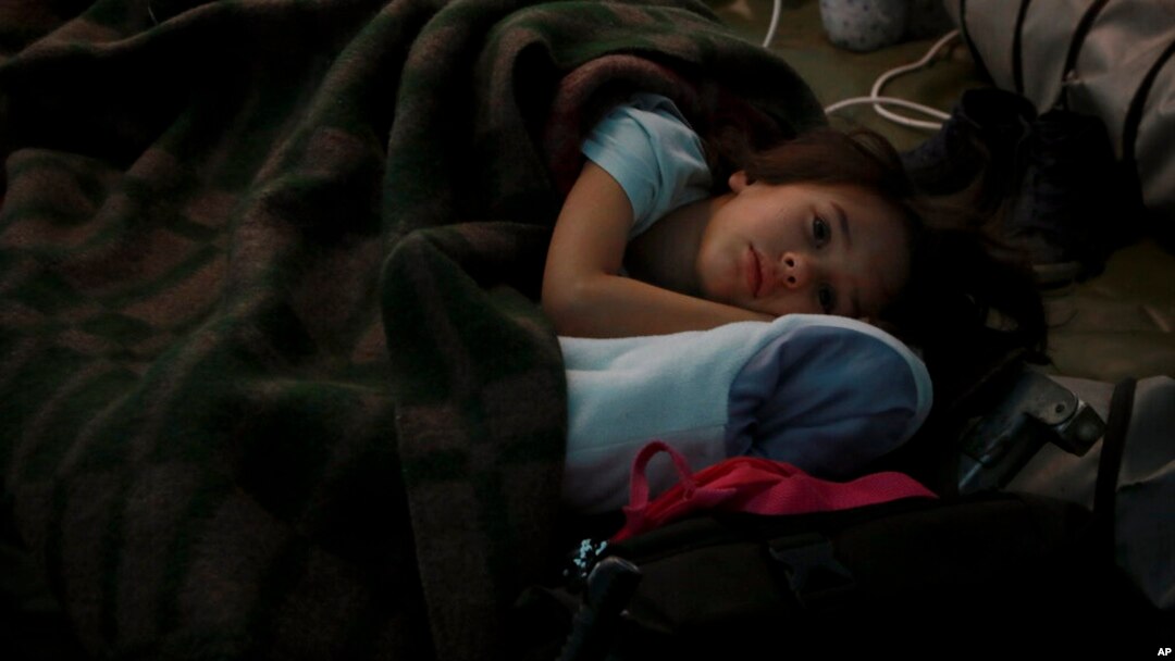 A child from Ukraine rests in a tent, part of a humanitarian center for refugees at the Moldovan-Ukrainian border, in Palalanca, Moldova, Feb. 25, 2022. Thousands of Ukrainians are fleeing from war by crossing their borders to the west in search of safety.