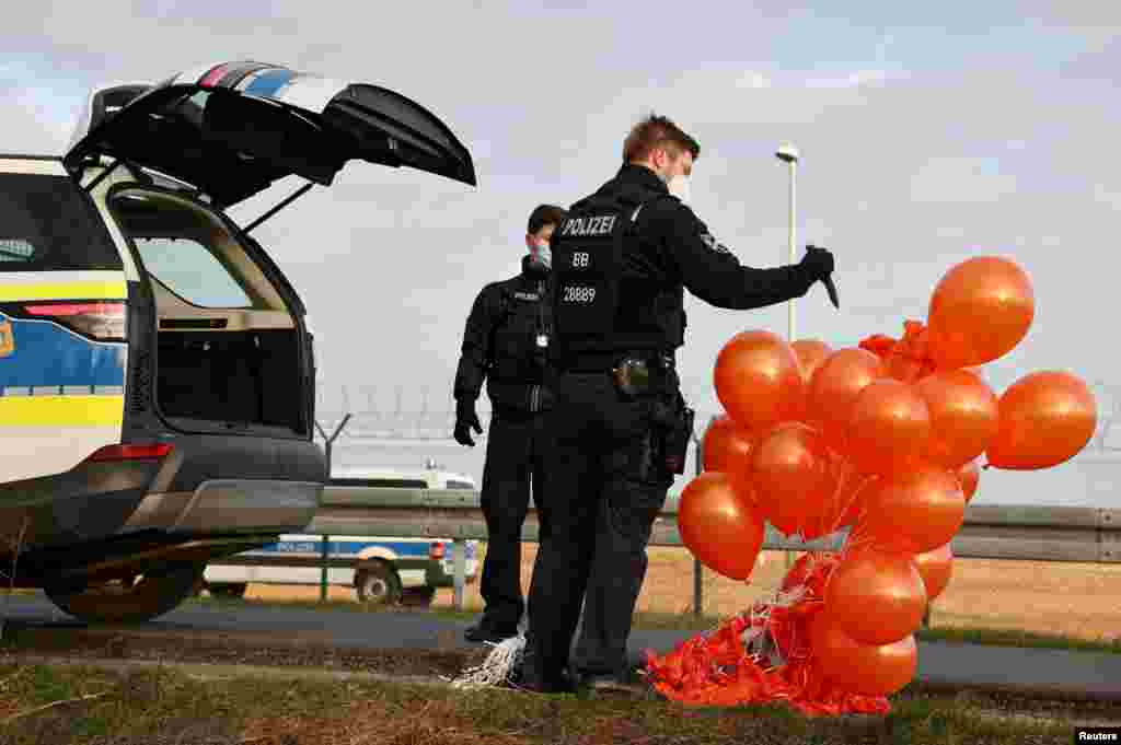 A police officer pops confiscated balloons following an activist's attempt to release balloons to interrupt air traffic at Berlin Brandenburg Airport to protest food waste and greenhouse gas emissions, in Berlin, Germany.