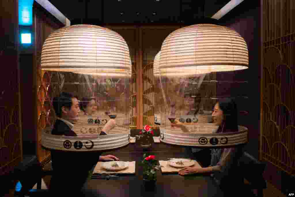 Staff members from the Hoshinoya Tokyo hotel demonstrate the "Lantern Dining Experience", where lanterns made by Kojima Shoten - a shop in Kyoto - are used to shroud diners for mask-free dining amid the Covid-19 pandemic, at the hotel in Tokyo, Japan.
