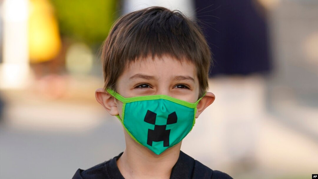 El estudiante de jardín de infantes Adam Shallbetter posa mientras su madre toma una foto después de llegar a la Escuela Primaria Whittier, el 24 de agosto de 2021, en Salt Lake City, Utah.