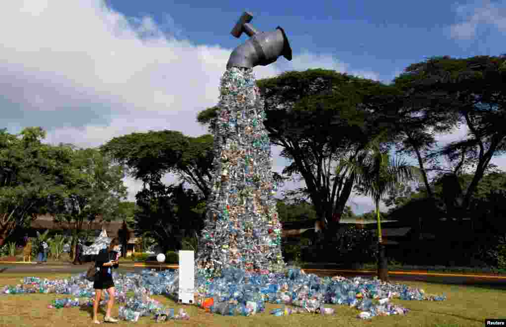 A delegate looks at a 30-foot monument dubbed "turn off the plastic tap" by Canadian activist and artist Benjamin von Wong, made with plastic waste collected from Kibera slums, at the venue of the Fifth Session of the United Nations Environment Assembly at the U.N. Environment Program Headquarters in Gigiri, Nairobi, Kenya.