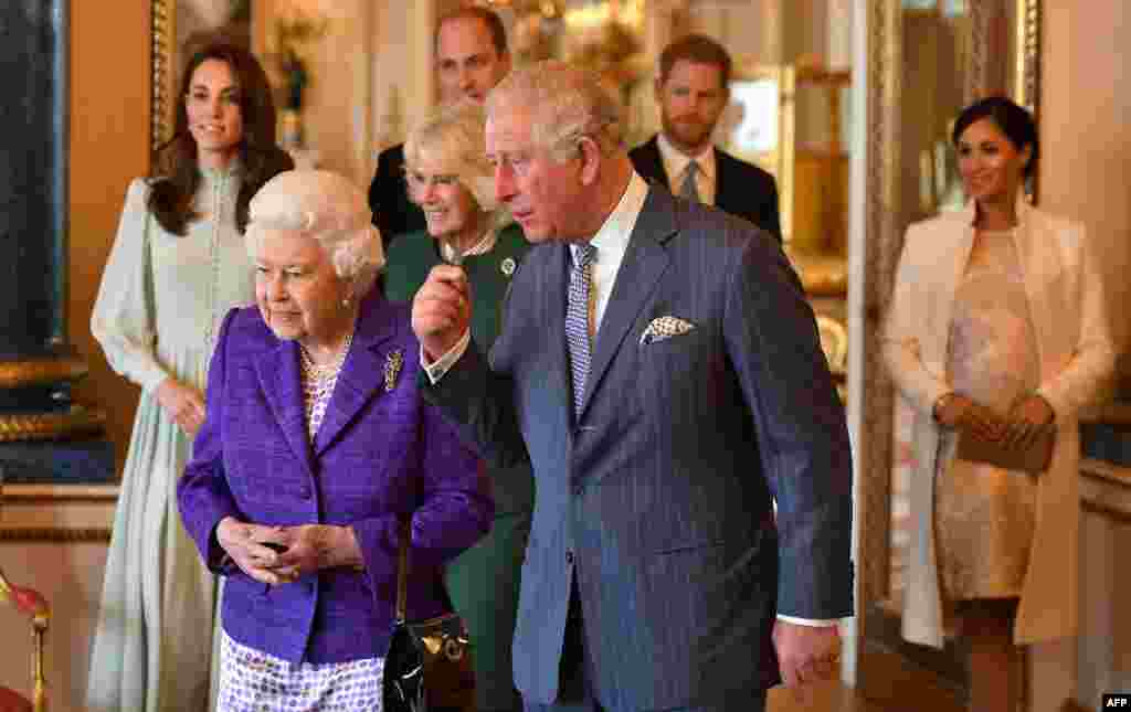 Britain's Prince Charles, Prince of Wales (C), walks with his mother Britain's Queen Elizabeth II (2L), and his wife Britain's Camilla, Duchess of Cornwall (3L), and his sons and their wives, Britain's Prince William, Duke of Cambridge (4L) and Britain's Catherine, Duchess of Cambridge (L), and Britain's Prince Harry, Duke of Sussex, (2R) and Meghan, Duchess of Sussex (R) during a reception to mark the 50th Anniversary of the investiture of The Prince of Wales at Buckingham Palace in London.