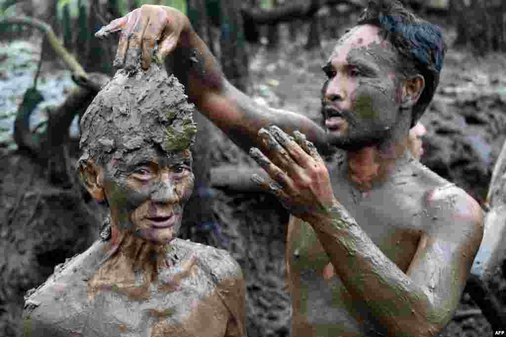 People take part in a mud bath tradition, known as Mebuug-buugan, held a day after Nyepi — the Balinese "Day of Silence" — aimed at neutralizing bad traits, in the village of Kedonganan on Indonesia's resort island of Bali