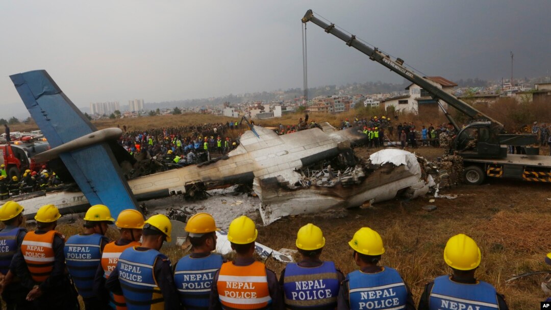 FILE- In this Monday, March 12, 2018 file photo, Nepalese rescuers and police are seen near the debris after a passenger plane from Bangladesh crashed at the airport in Kathmandu.