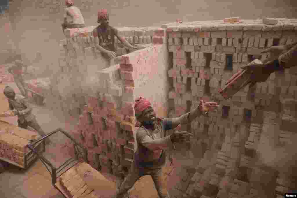 Brick factory workers stack bricks on a cart to take them to the warehouse in Dhaka, Bangladesh.