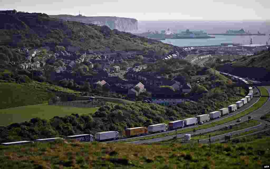 Freight lorries and HGVs (heavy goods vehicles) queue on the A20 road towards the Port of Dover, as the P&O ferry 'Spirit of Canterbury' (R) is pictured moored to the quayside at the port, on the south-east coast of England.