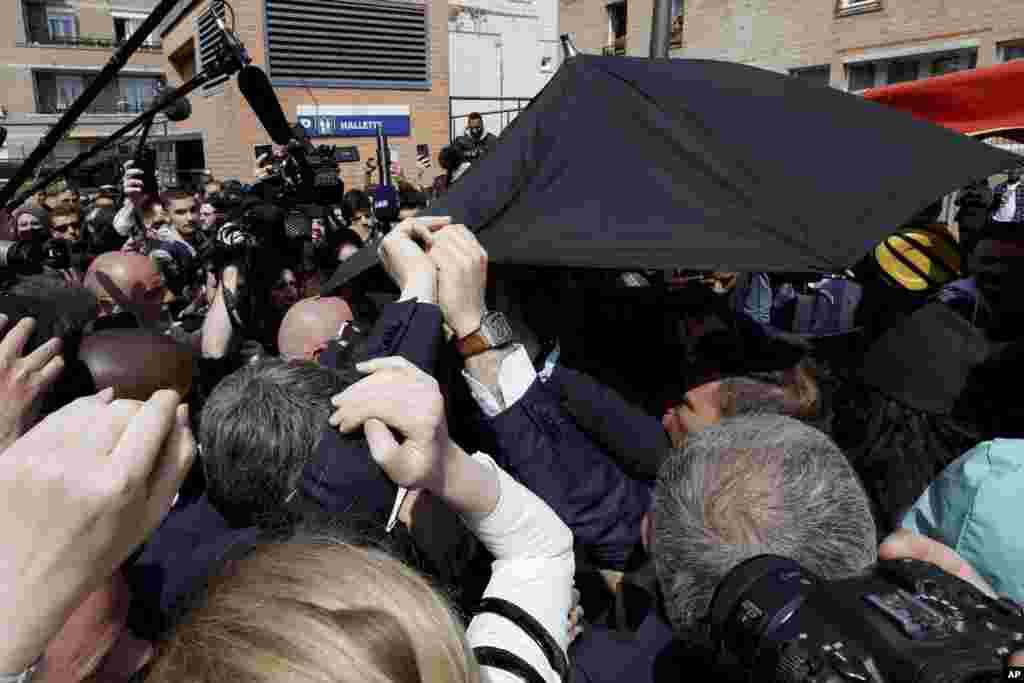 French President Emmanuel Macron is protected with an umbrella after a projectile was thrown during a walkabout at the Saint-Christophe market square in Cergy, a Paris suburb.