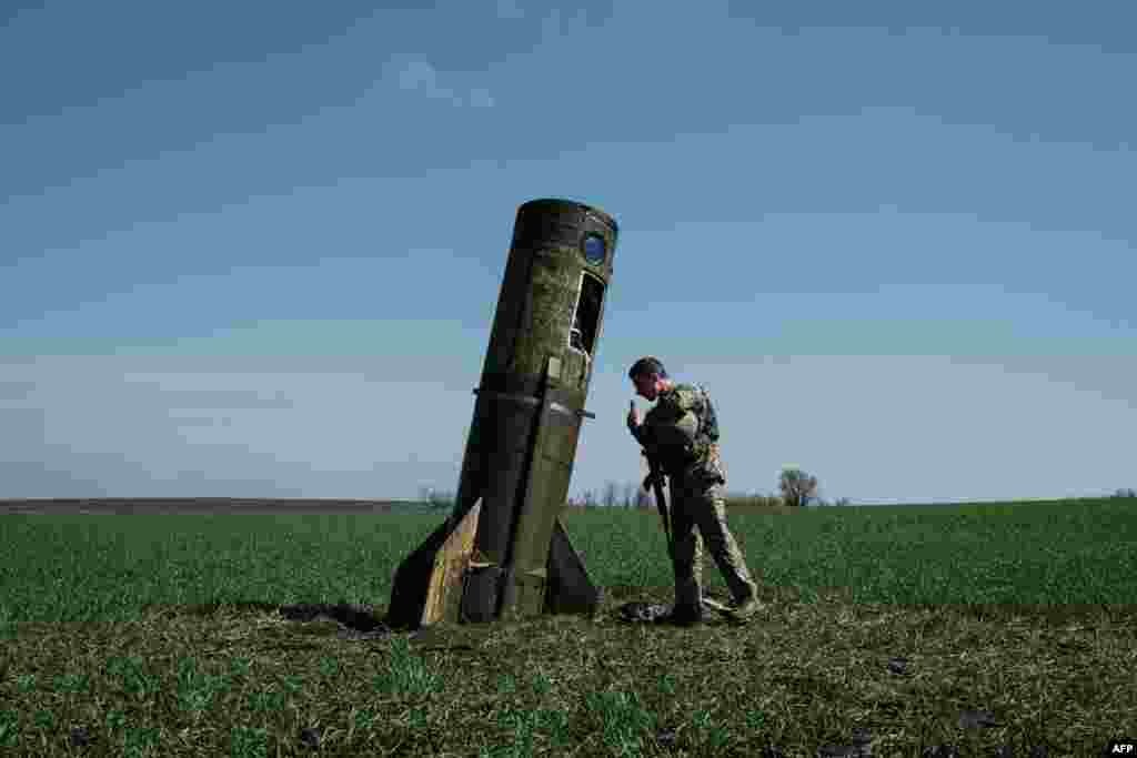 A Ukrainian serviceman looks at a Russian ballistic missile's booster stage that fell in a field in Bohodarove, eastern Ukraine, amid the Russian invasion of Ukraine.