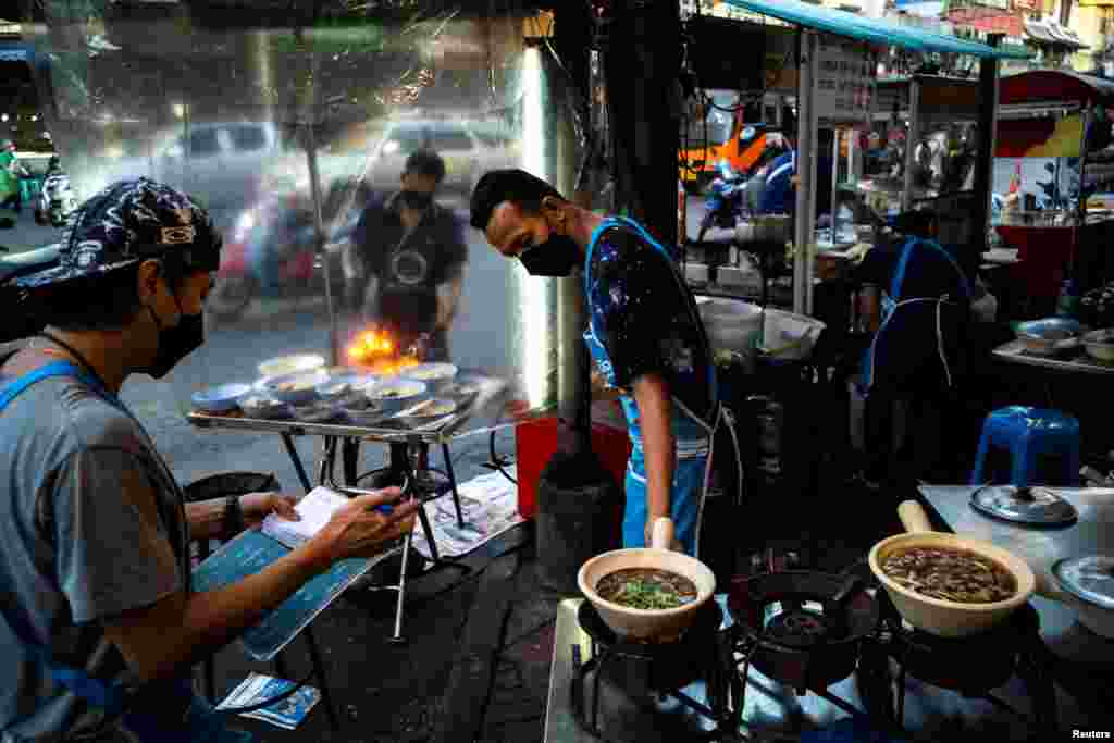 People wearing face masks as protection against the COVID-19 sell street food in Bangkok's Chinatown, Thailand.