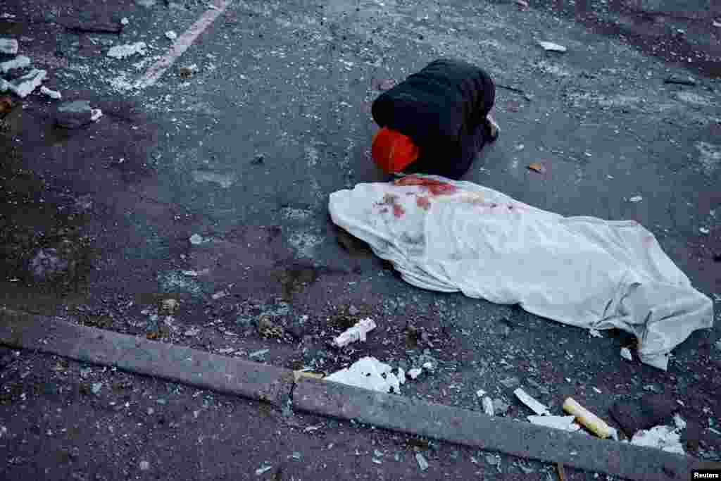 A man mourns next to the body of his mother, who was killed when a Russian missile hit a residential building in Kyiv, amid Russia's invasion of Ukraine.