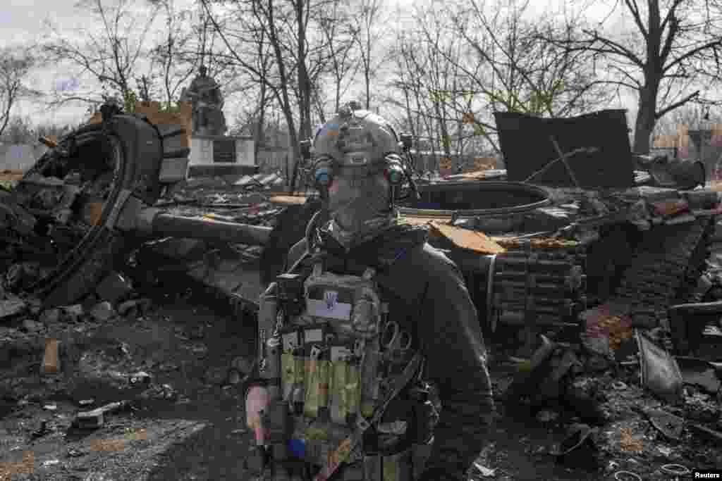 A Ukranian serviceman walks past the wreckage of a Russian tank in the village of Lukyanivka outside Kyiv, as Russia's invasion of Ukraine continues, March 27, 2022.