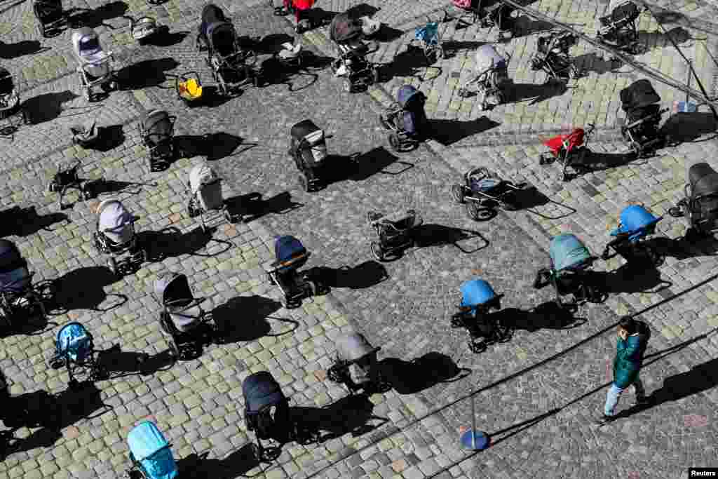 A person looks at 109 empty baby carriages placed in the center of Lviv, Ukraine, to highlight the large number of children killed in ongoing Russia's invasion of Ukraine.