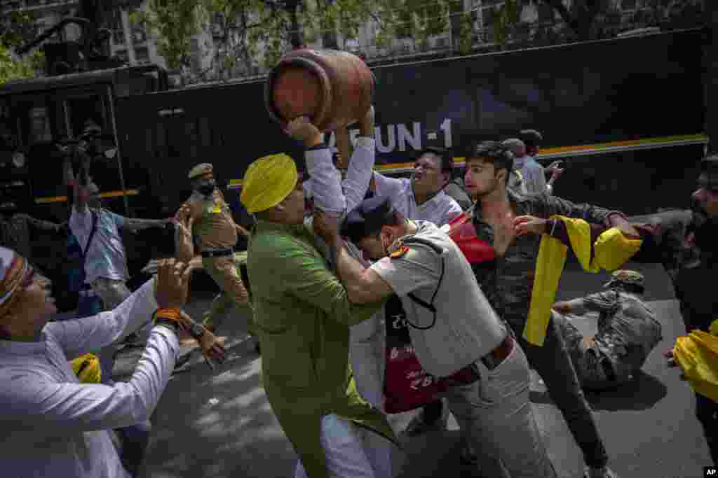 A Delhi police officer tries to stop an opposition Congress party supporter with an empty Liquefied Petroleum Gas (LPG) cylinder over his head during a protest against rising inflation and price hike of essential commodities, in New Delhi, India.