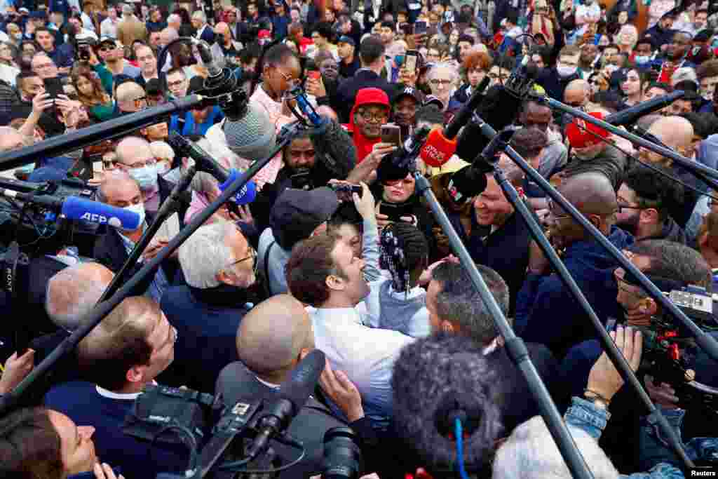 French incumbent president and candidate for the 2022 presidential election Emmanuel Macron carries a girl during a meeting with supporters as he campaigns in Dijon.