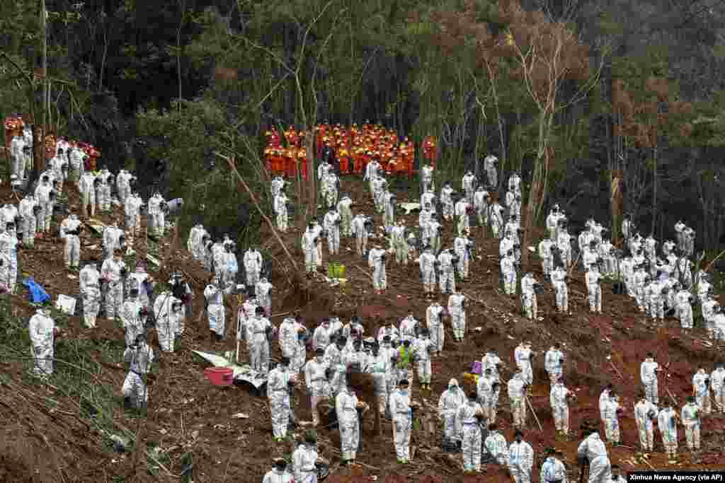 Search and rescue workers pause for a three-minute moment of silence for the 132 people killed at the China Eastern flight crash site in Tengxian County in southern China's Guangxi Zhuang Autonomous Region. The second "black box" from a China Eastern Boeing 737-800 was found, raising hopes that it might shed light on why the passenger plane nosedived into a remote mountainous area last week.