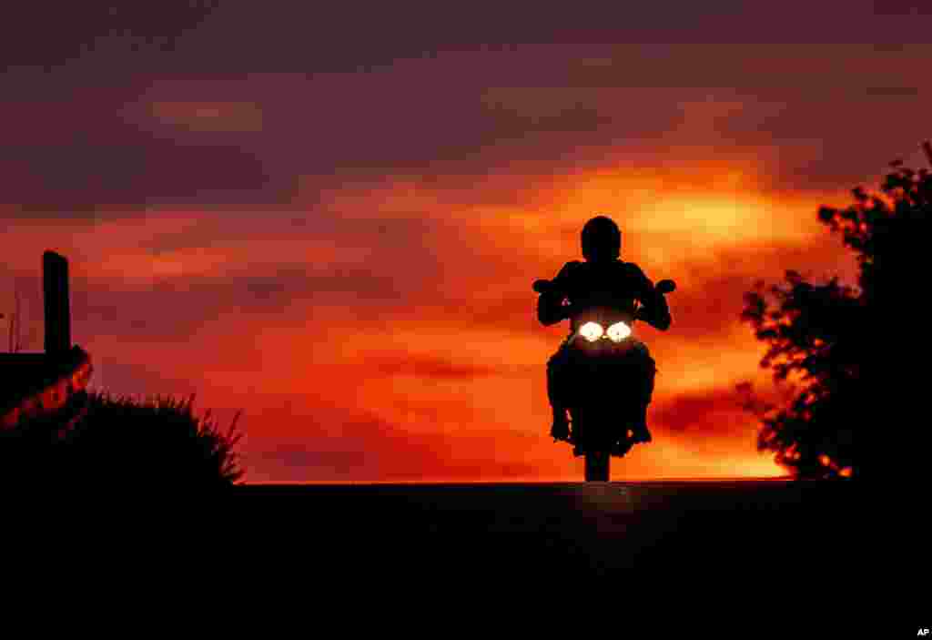 A man rides his bike over a hill on the outskirts of Frankfurt, Germany, as the sun rises.
