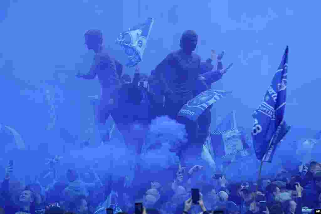 Fans use smoke flares as they gather for the Premier League soccer match between Everton and Chelsea outside the Goodison Park in Liverpool, England.