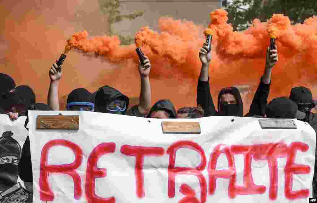 Protesters hold smoke bombs and a banner reading "retirement at 20" as they take part in the traditional May Day rally in Nantes, western France.
