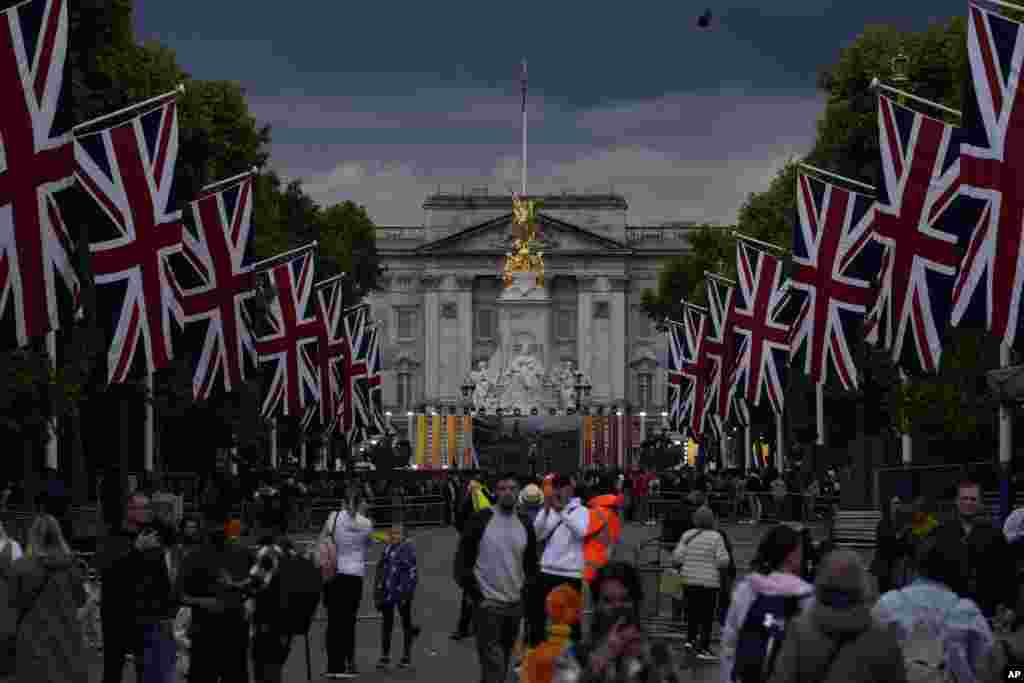 People look at the Buckingham Palace and the Queen Victoria Memorial statue as the road is lined with Union flags and closed to traffic ahead of Britain's Queen Elizabeth II's Platinum Jubilee, in London.