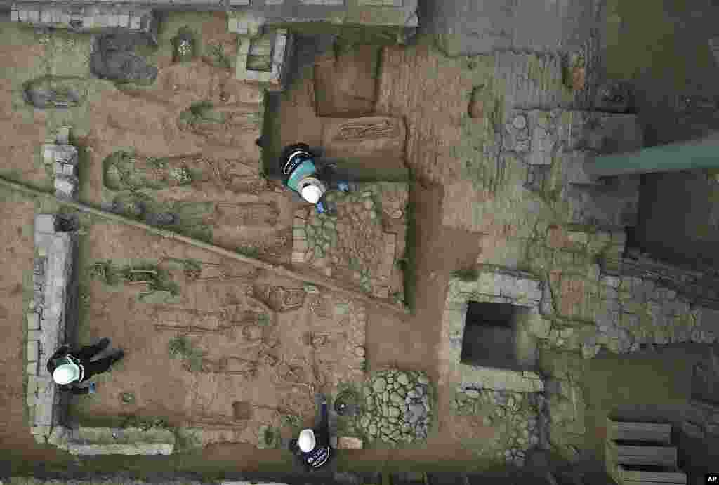 City workers excavate bones discovered in the foundation of the building that held the former San Andres Royal Hospital in downtown Lima, Peru.