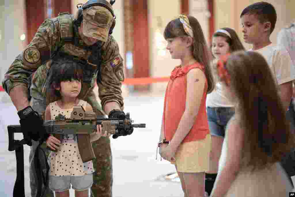A girl poses with a weapon at a stand set up by Romania's army special forces at the Palace of the Parliament on International Children's Day in Bucharest.