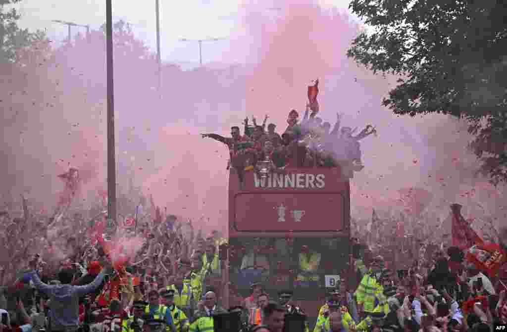 Liverpool's players celebrate winning the 2021-22 League Cup and FA Cup from an open-top bus with supporters during a parade through the streets of Liverpool in north-west England.