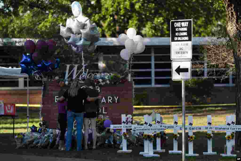 A family pays their respects next to crosses bearing the names of Tuesday's shooting victims at Robb Elementary School in Uvalde, Texas.