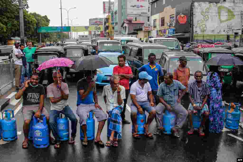 People sit on empty Liquified Gas Cylinders as they block a road to protest a shortage of fuel and cooking gas in Colombo, Sri Lanka.