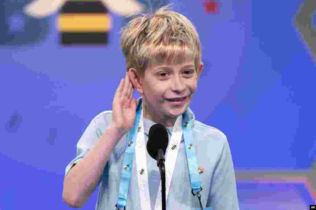 Miles Hubbert, 10, from Centreville, Md., says "what?," and cups his ear on hearing his word as he competes during the Scripps National Spelling Bee, in Oxon Hill.