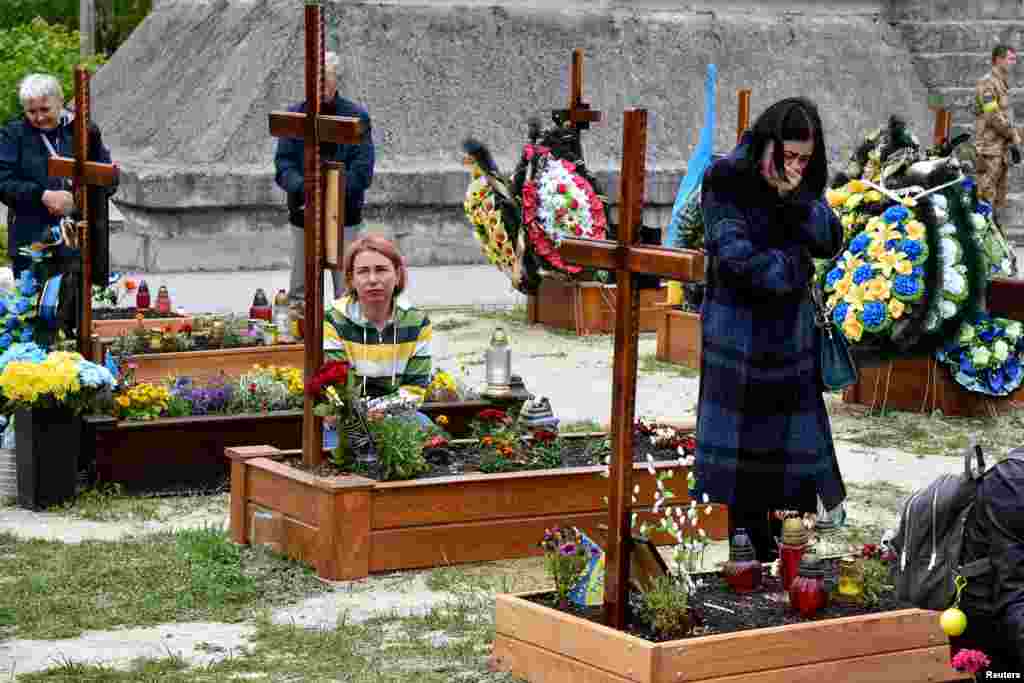 People pay respect to graves at Lychakiv Cemetery where some people killed in Russia's invasion of Ukraine are buried as the Day of Heroes of Heavenly Hundred is celebrated in Lviv, Ukraine.